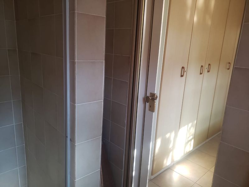 A functional hallway featuring built-in cupboards and tiled finishes, providing ample storage space and a clean, neutral aesthetic.
