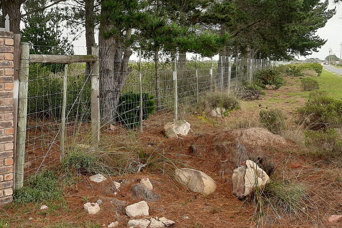 Street-level view of the property boundary featuring a brick pillar and wire mesh fencing along the roadside.