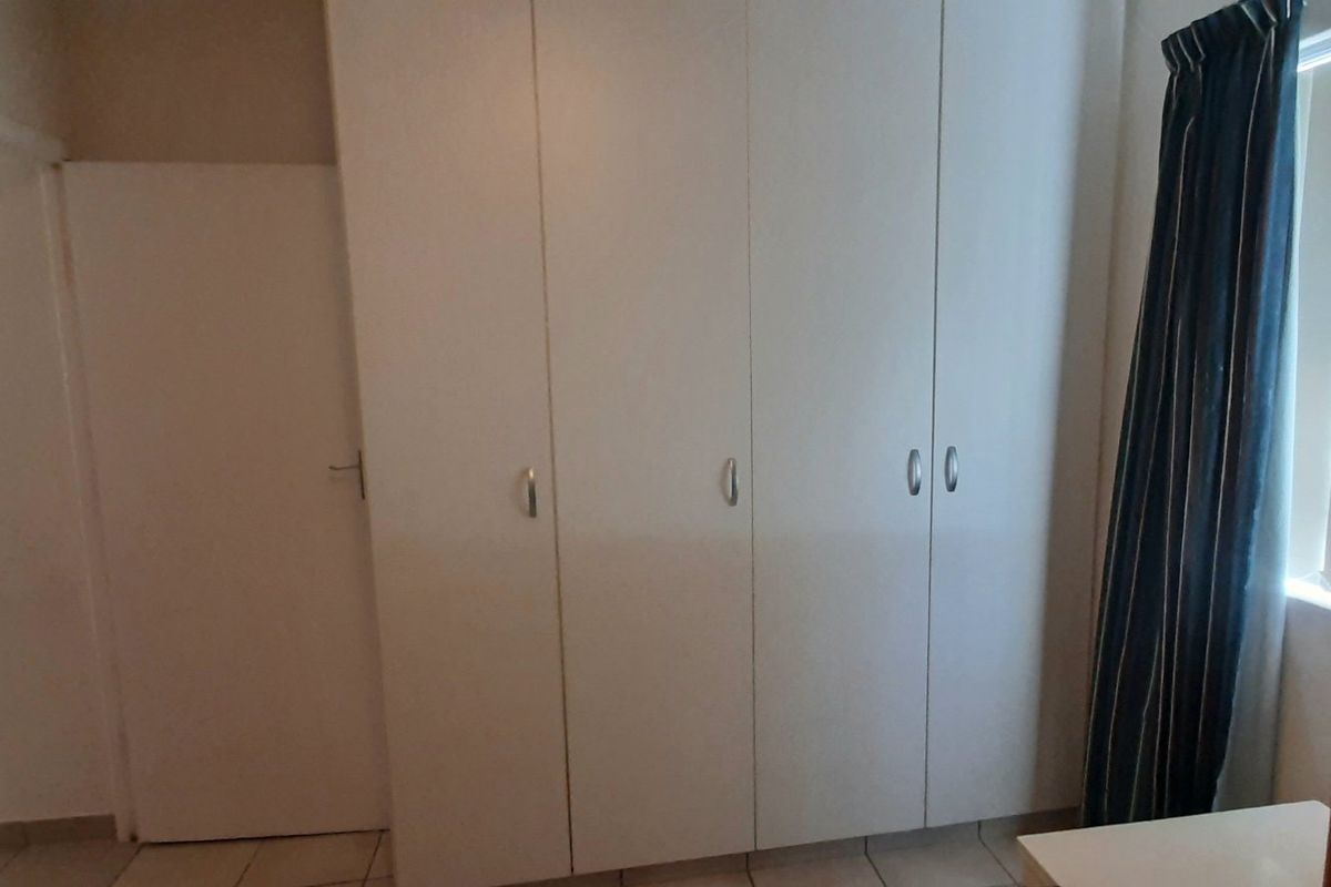 A bedroom featuring built-in white cabinetry and tiled flooring, offering functional storage space.