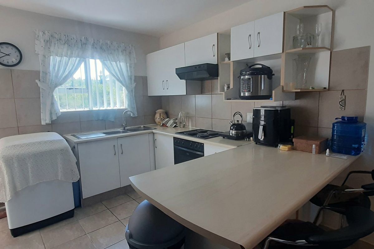 A functional kitchen featuring white cabinetry, a built-in hob and oven, tiled backsplash, and an integrated breakfast bar counter.