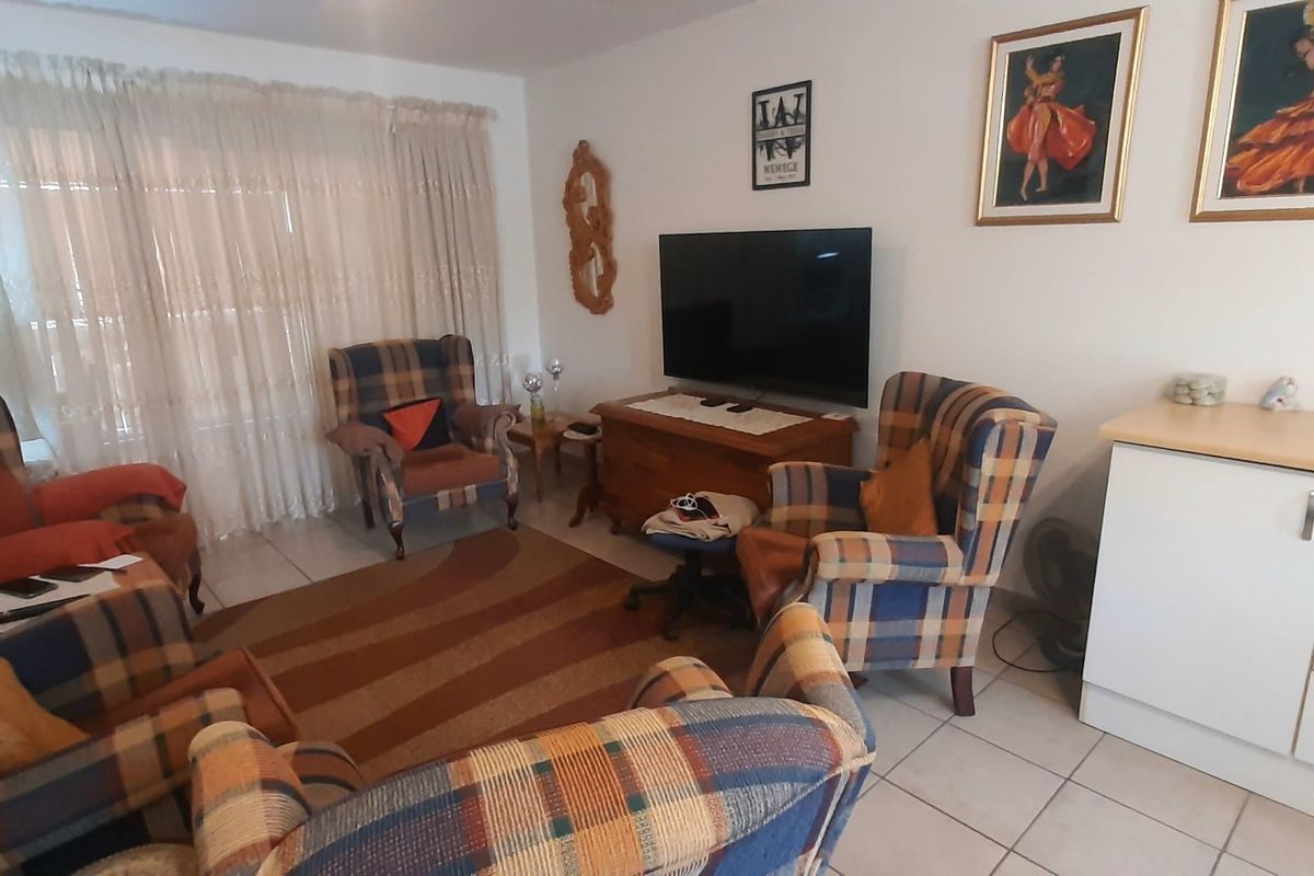 A living room featuring tiled flooring and a built-in white storage cabinet with a light wood-tone countertop.