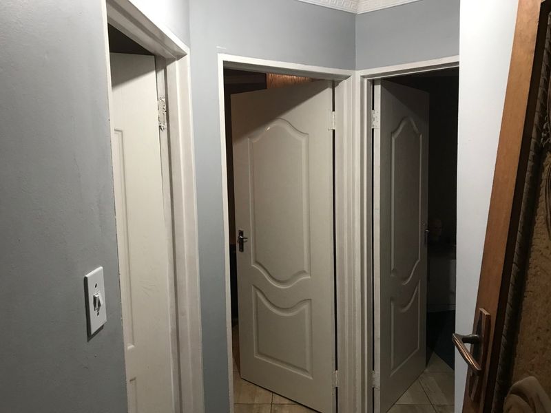 A functional hallway featuring multiple interior doors, tiled flooring, and neutral wall finishes, providing access to various rooms within the townhouse.