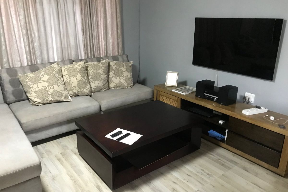 A comfortable living room featuring light-toned laminate flooring and neutral wall finishes, providing a clean and functional space for relaxation.