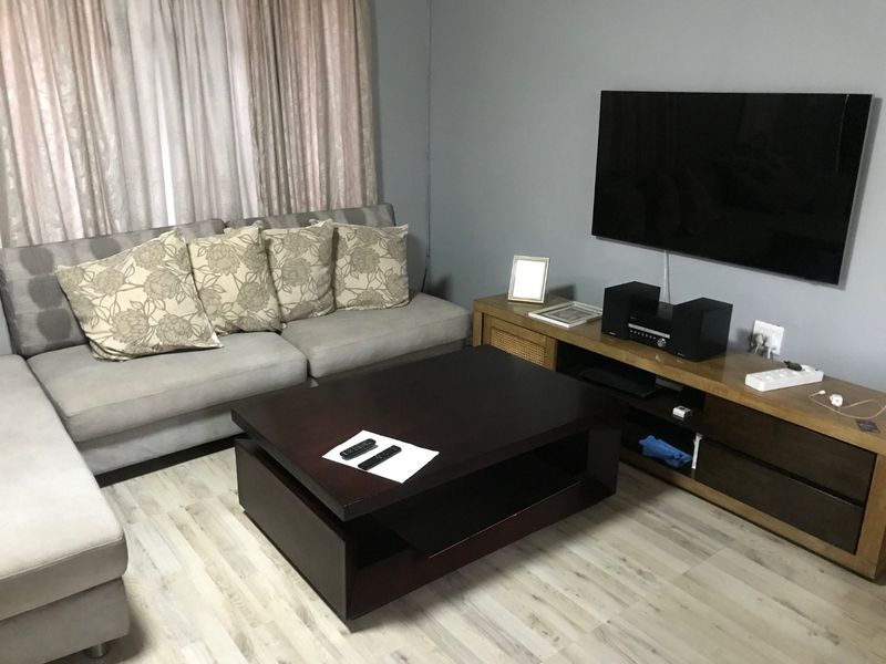A comfortable living room featuring light-toned laminate flooring and neutral wall finishes, providing a clean and functional space for relaxation.