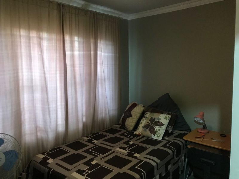 A standard bedroom featuring neutral wall paint, decorative cornice detailing, and a window with curtains.