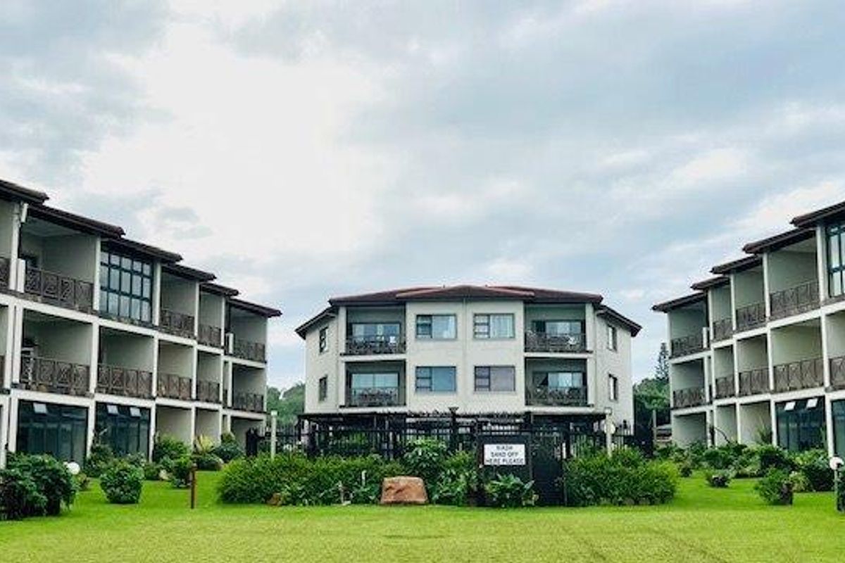 A view of the apartment complex exterior featuring multiple levels of balconies, large sliding glass doors, and a well-maintained central garden area.