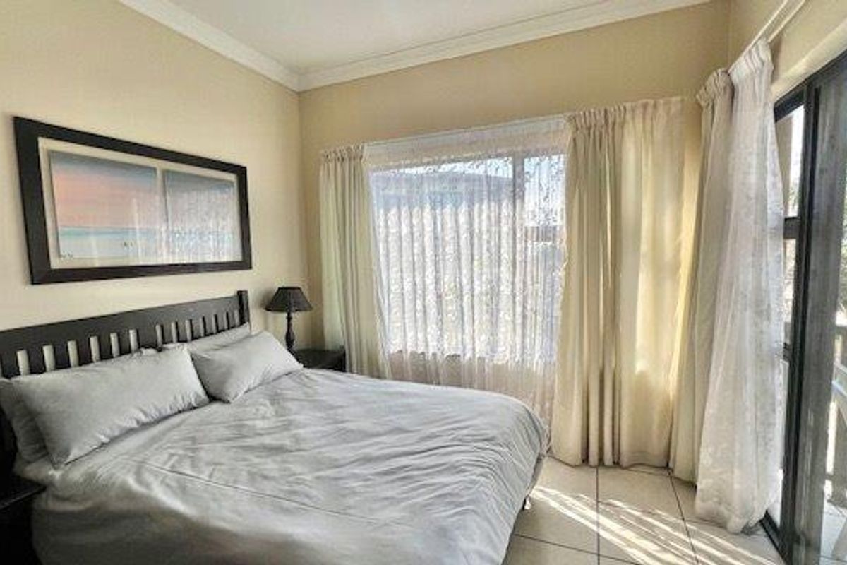 A bedroom featuring tiled flooring and a large sliding glass door providing access to an outdoor balcony area.