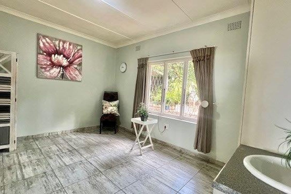 A functional kitchen area featuring tiled flooring, a built-in sink with laminate countertop, and neutral wall finishes with coved ceiling cornices.