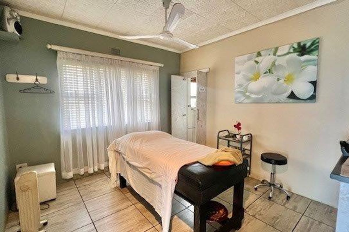 A functional bedroom space featuring tiled flooring, a ceiling fan, and built-in storage, currently utilized as a treatment room.