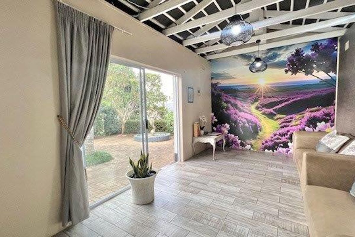 Living area featuring exposed beam ceilings, tiled flooring, and a large sliding glass door providing direct access to the garden.