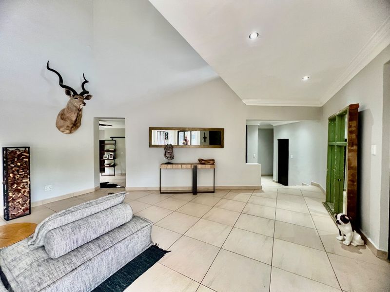 Spacious living area featuring high vaulted ceilings, neutral tiled flooring, and recessed lighting, creating an open and airy atmosphere.