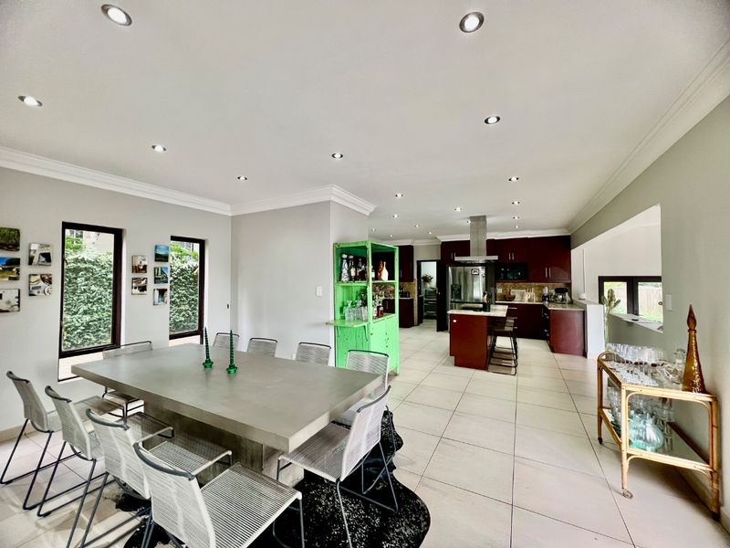 Spacious open-plan living and dining area featuring tiled floors, recessed lighting, and a modern kitchen with a central island and dark cabinetry.