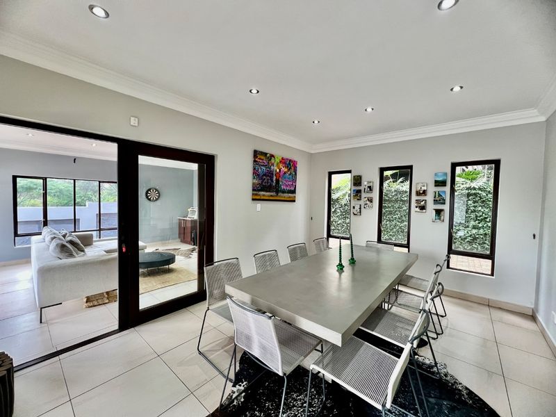 Spacious dining room featuring tiled flooring, recessed downlighting, and large sliding glass doors providing seamless access to the adjacent living area.