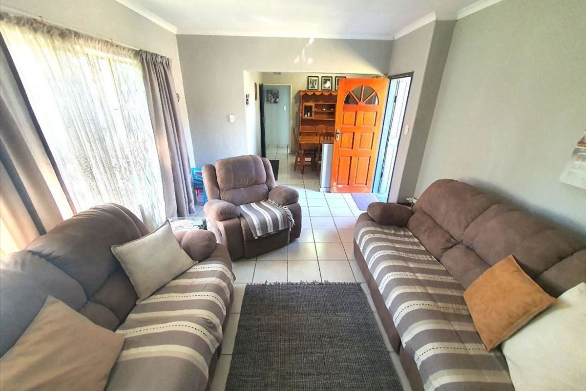 A living room area featuring tiled flooring, neutral wall tones, and direct access to the home entrance.