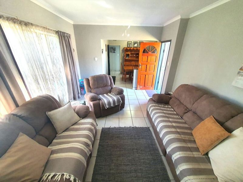 A living room area featuring tiled flooring, neutral wall tones, and direct access to the home entrance.