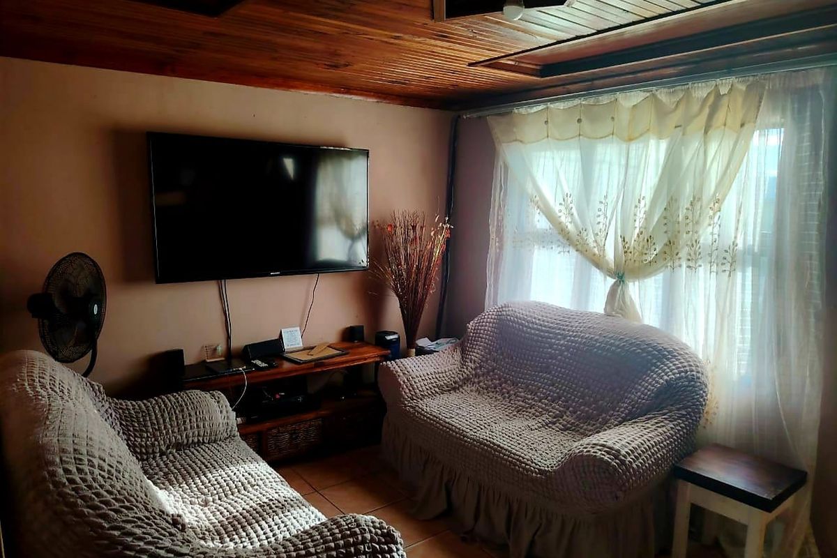 A cozy living room featuring a warm timber-clad ceiling and tiled flooring, providing a comfortable and inviting space.