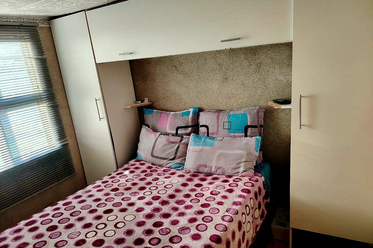 Bedroom featuring built-in cupboards with overhead storage and venetian blinds.