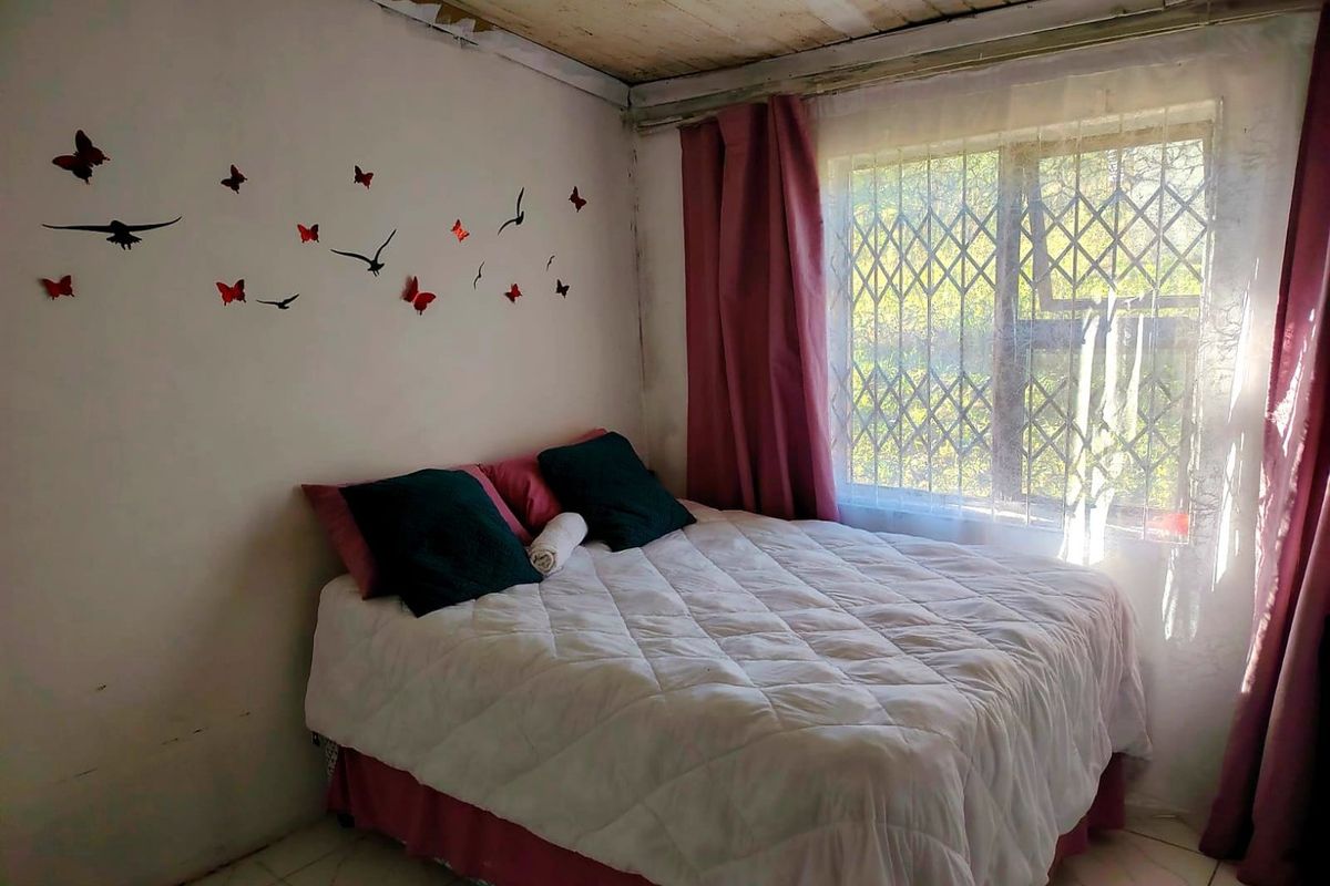A bedroom featuring tiled flooring, a timber ceiling, and a window fitted with a security gate.