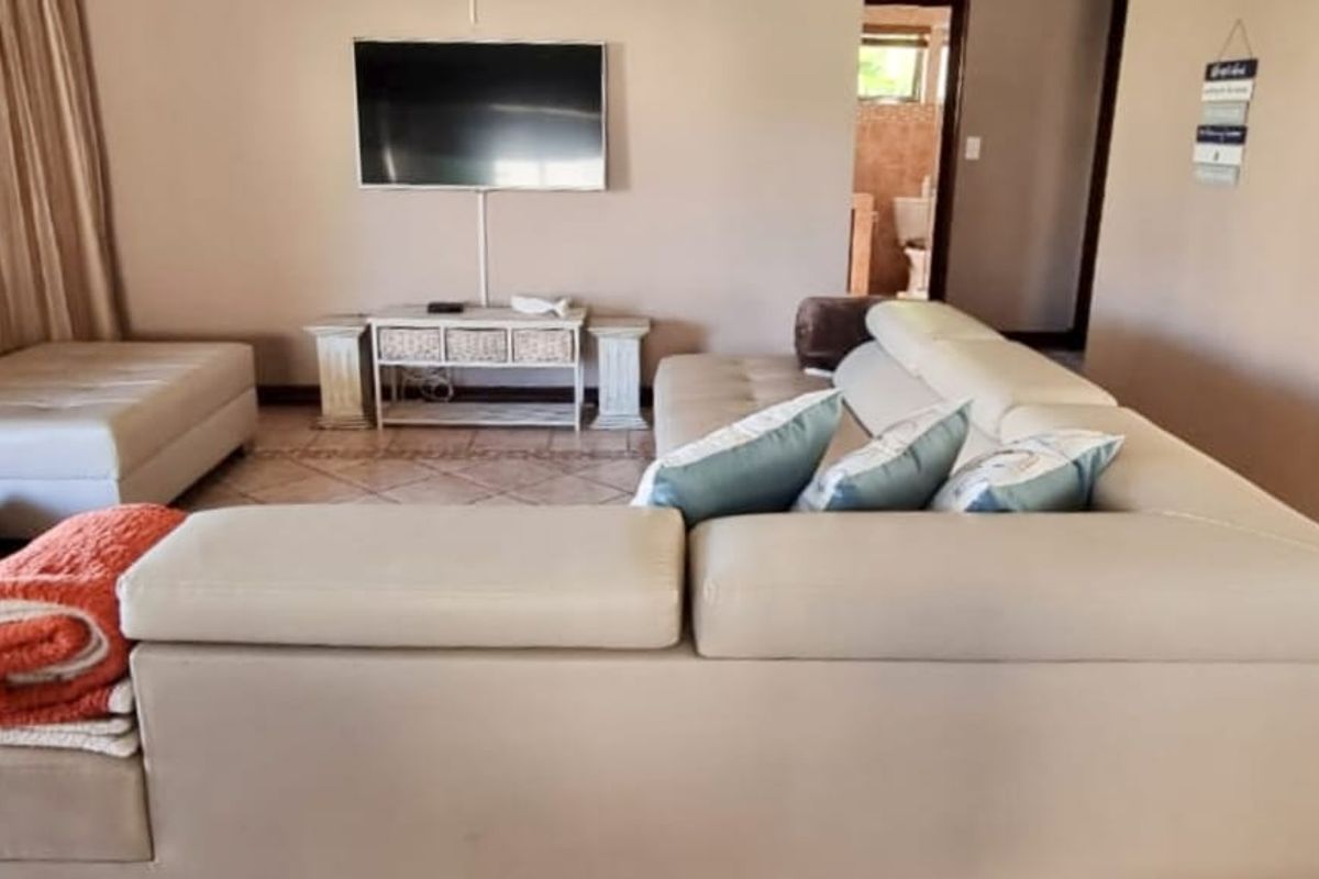 A comfortable living room featuring tiled flooring and a wall-mounted television, providing a functional space for relaxation.