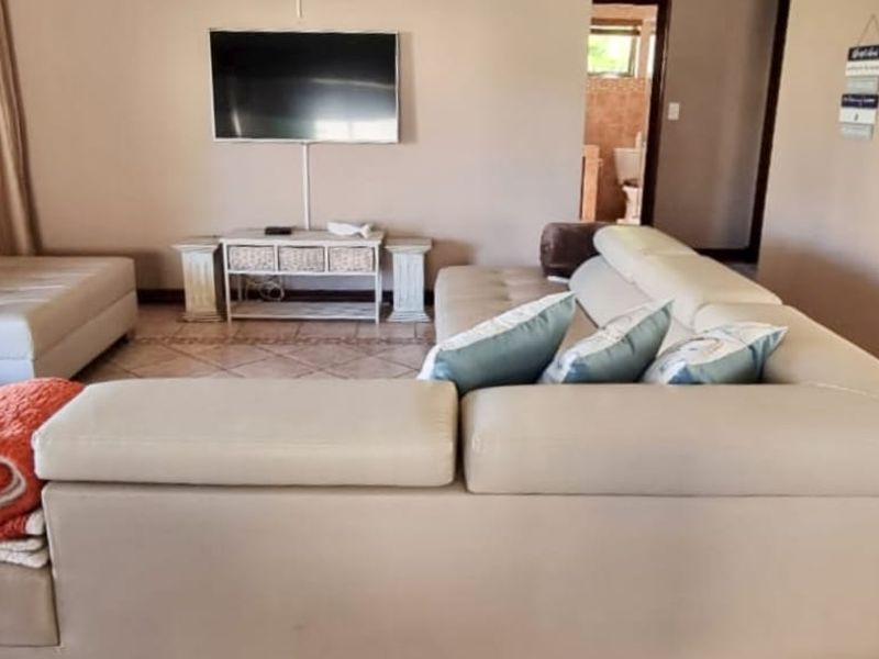 A comfortable living room featuring tiled flooring and a wall-mounted television, providing a functional space for relaxation.