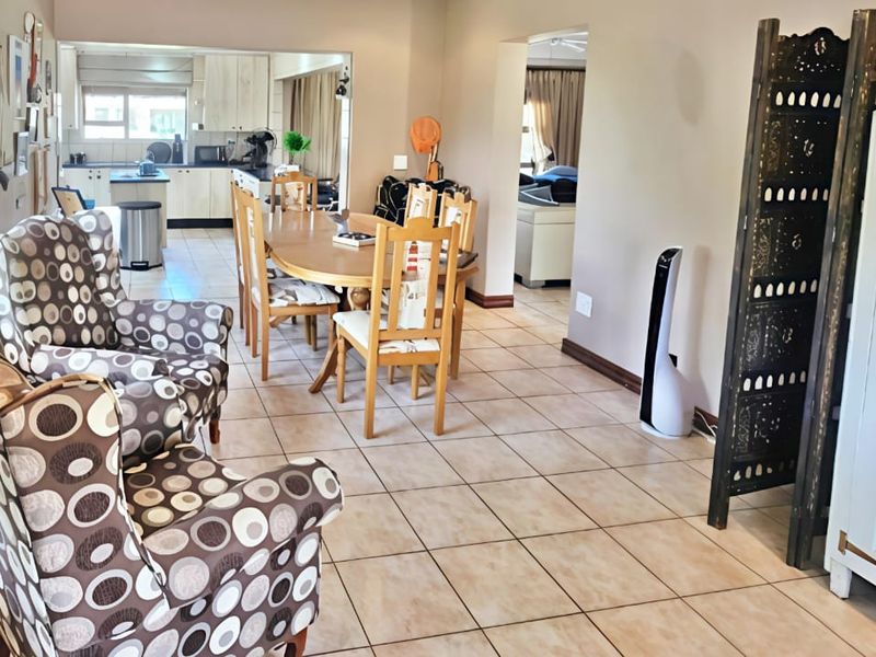 An open-plan living and dining area featuring tiled flooring, flowing into a functional kitchen space with built-in cabinetry and an island.