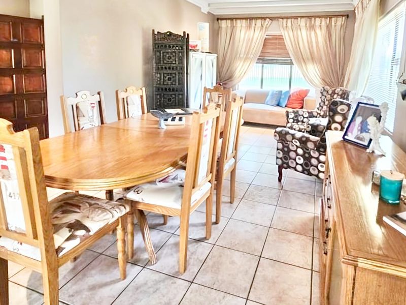 A dining room area featuring tiled flooring, a wooden door, and window blinds, providing a functional space for meals and gatherings.