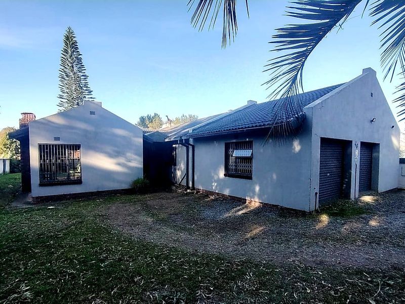 Front exterior view of a single-story house featuring a double garage, tiled roof, and security bars on windows.