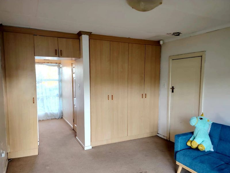 Bedroom featuring built-in wooden cupboards and carpeted flooring, showing signs of wear and ceiling damage requiring maintenance.