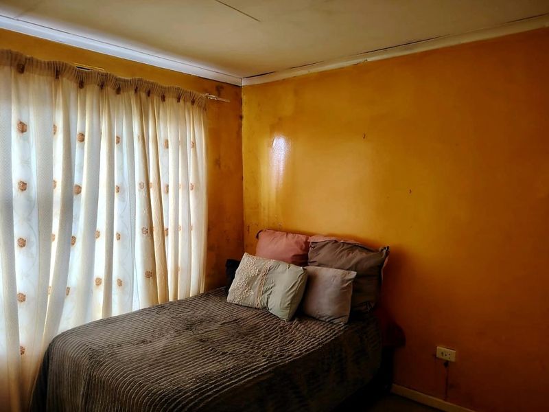 A bedroom featuring yellow walls with visible surface wear and ceiling staining, requiring cosmetic updates to improve the overall condition.