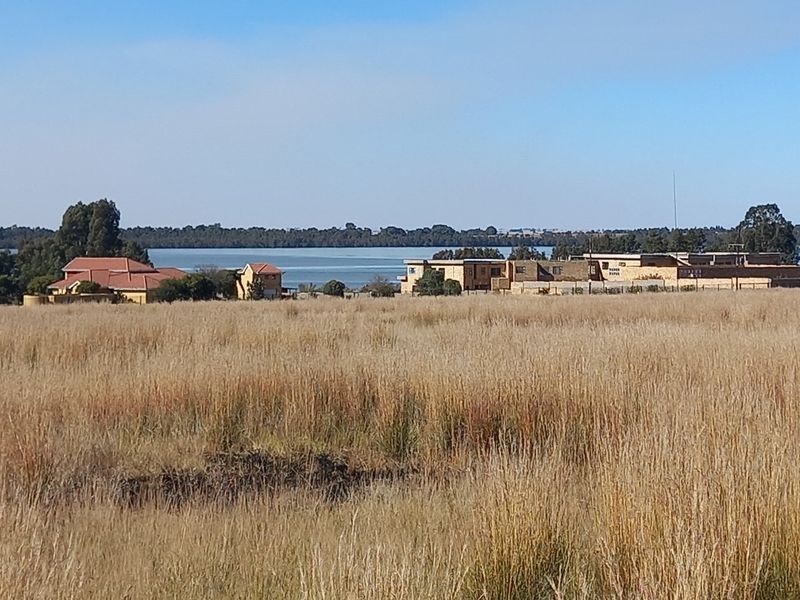 A scenic view of the surrounding landscape featuring open fields and a distant water body, showcasing the natural setting of the vacant land.