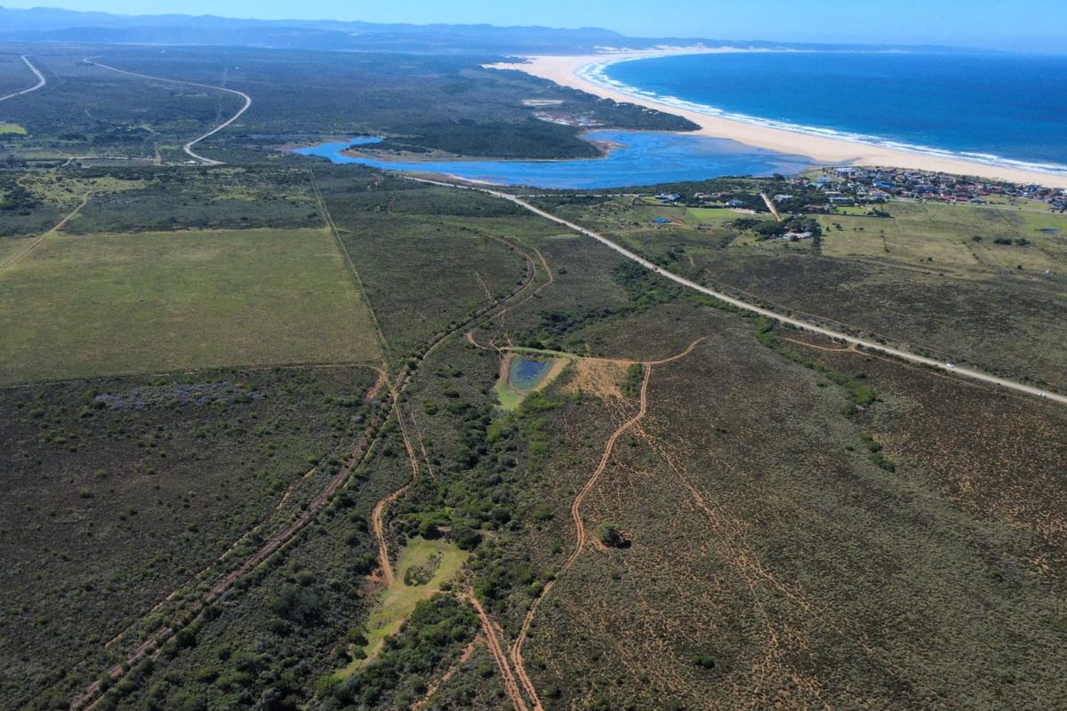 Aerial view of the expansive farm property, showcasing the natural landscape, access roads, and proximity to the coastline and river estuary.