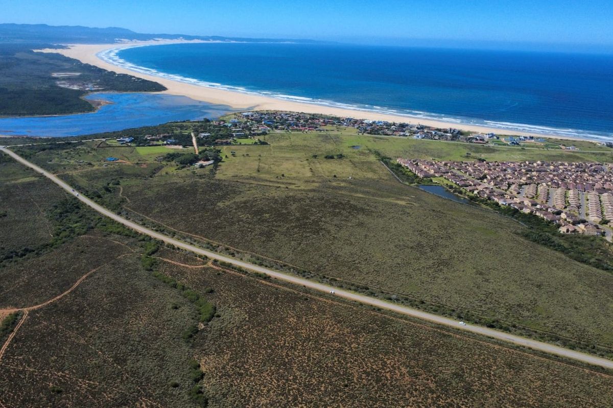 An expansive aerial view of the coastal farm property, showcasing its proximity to the coastline, local estuary, and surrounding residential developments.