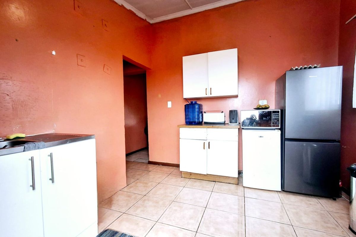 A functional kitchen space featuring tiled flooring, white cabinetry, and a dedicated area for appliances.