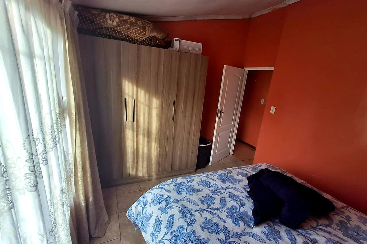 A bedroom featuring tiled flooring, built-in wooden cabinetry, and a doorway leading to an adjacent space.