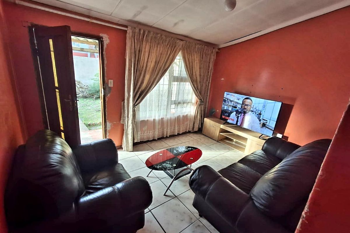 A living room featuring tiled flooring, a large window with curtains, and direct access to the outdoor area.