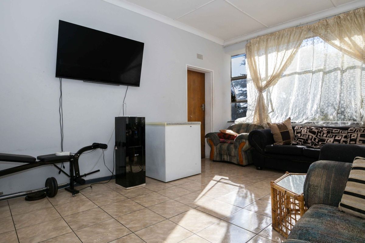 A living room featuring tiled flooring and a coved ceiling, offering a functional space with natural light from the large window.