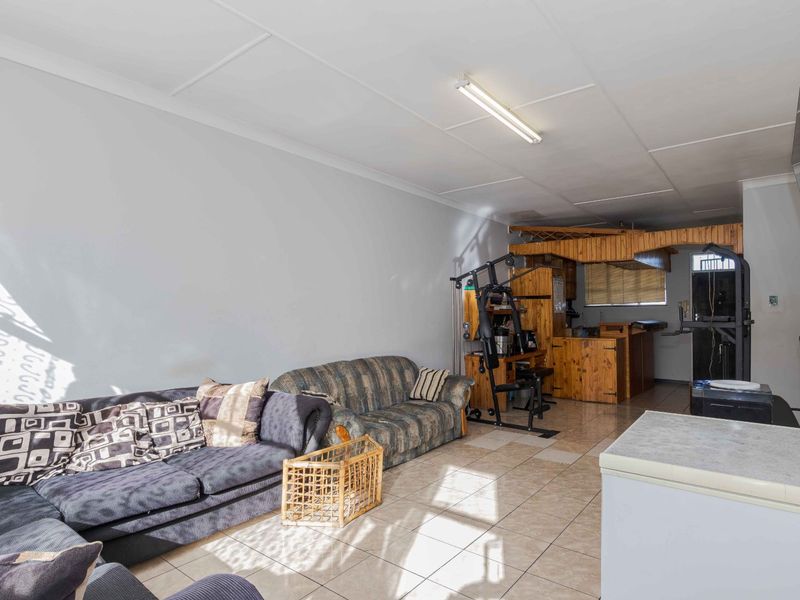 Open plan living area featuring tiled flooring and a timber kitchen counter, offering a functional layout with potential for modern updates.