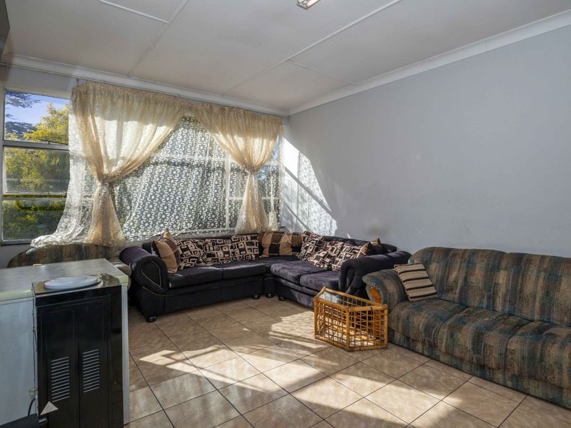 A living room area featuring large windows and tiled flooring, requiring cosmetic updates to improve the overall aesthetic and finish.
