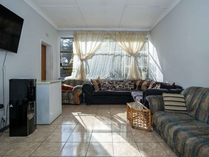 A living room featuring tiled flooring and a large window, requiring cosmetic updates to the ceiling and general finishes to improve the space.