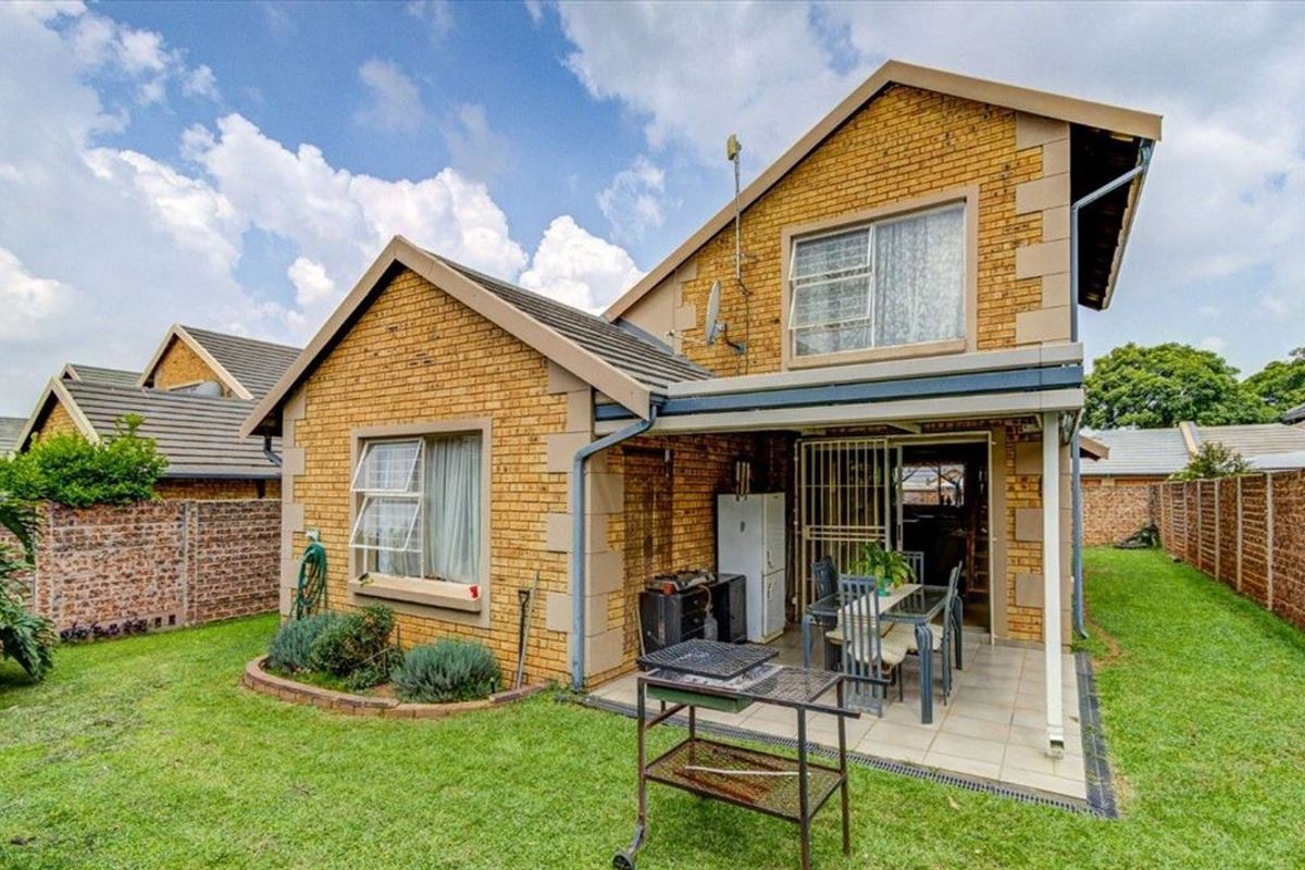 Rear view of a face brick townhouse featuring a covered patio, private garden, and secure access points.
