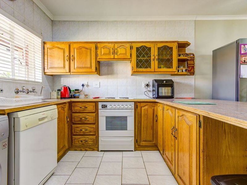A functional kitchen featuring traditional wooden cabinetry, tiled backsplash, built-in oven, and ample counter space, offering a classic layout ready for modern updates.