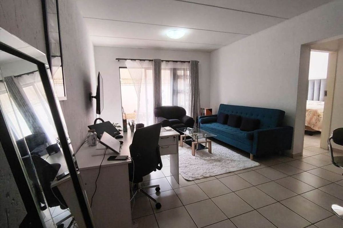 A functional living room featuring tiled flooring and a sliding glass door providing access to the exterior.