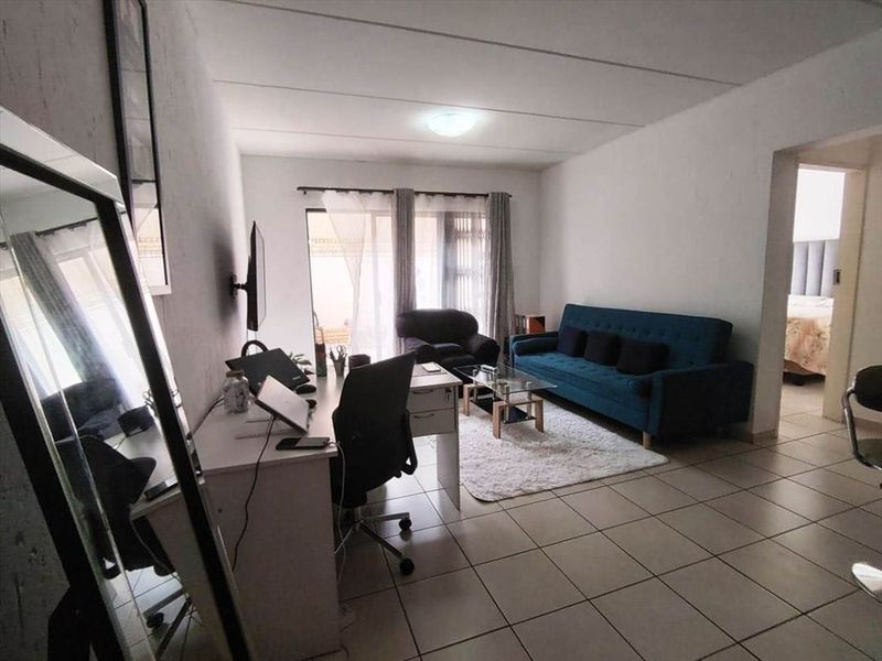 A functional living room featuring tiled flooring and a sliding glass door providing access to the exterior.