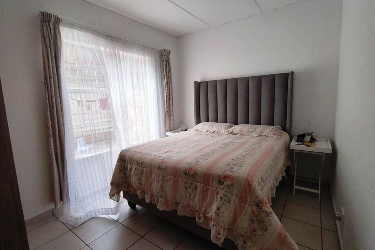 A functional bedroom featuring tiled flooring and a large sliding glass door providing natural light and access to the exterior.