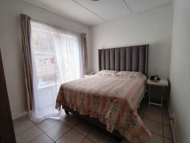 A functional bedroom featuring tiled flooring and a large sliding glass door providing natural light and access to the exterior.