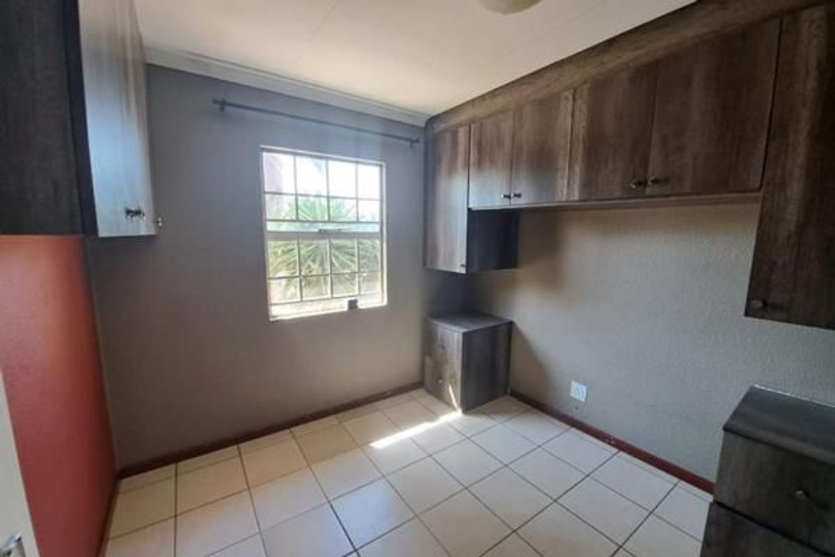 A vacant bedroom featuring built-in wooden cabinetry, tiled flooring, and a window providing natural light.