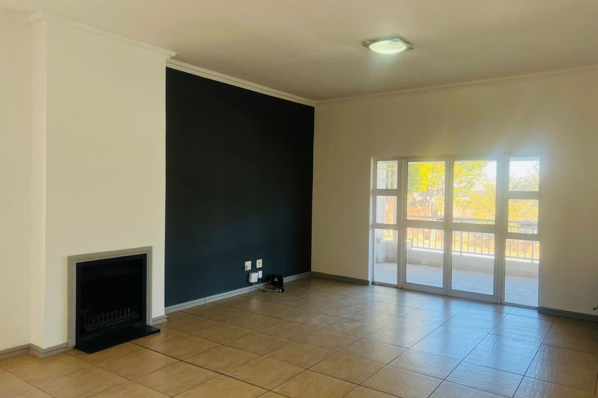 Spacious living room featuring tiled flooring, a built-in fireplace, and large sliding glass doors that provide access to an outdoor balcony area.