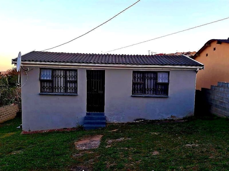 A single-story residential house featuring a tiled roof, security gates on windows and doors, and a surrounding grass yard.