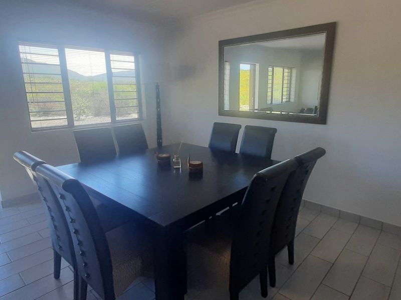 A dining room featuring tiled flooring, a large window with natural light, and a sliding glass door providing access to the exterior.