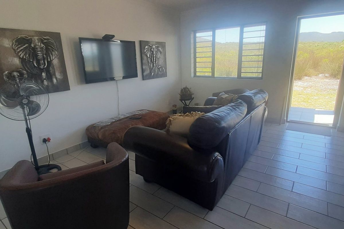 A living room featuring tiled flooring, aluminium window frames with security bars, and a glass sliding door providing access to the exterior.